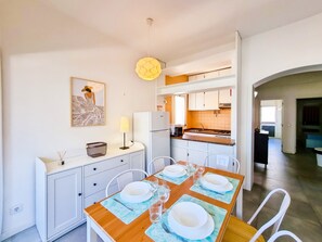 A modern kitchen with white cabinets, a dining table set for four, and a kitchen island.
