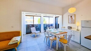 Un espace de vie compact comprenant un coin repas, une kitchenette et un balcon avec vue.