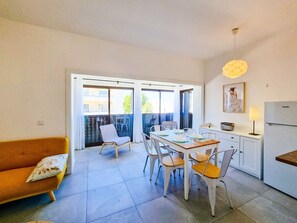 A compact living space with a dining area, kitchenette, and a balcony with a view.
