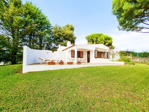 A modern white house with a patio, outdoor seating, and a well-maintained lawn.
