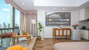 A modern hotel room with a large window, a flat-screen TV mounted on the wall, a wooden cabinet, and a bed with a beige blanket. - Zhiling Homestay (Five Star Street City Center) (Liuzhou)