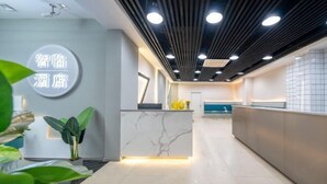 A modern reception area with a marble counter, a large illuminated sign, and a ceiling with recessed lighting. - Zhiling Homestay (Five Star Street City Center) (Liuzhou)