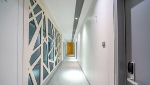 A modern hotel corridor with a geometric patterned wall, a door with a card reader, and a bright hallway leading to a room. - Zhiling Homestay (Five Star Street City Center) (Liuzhou)