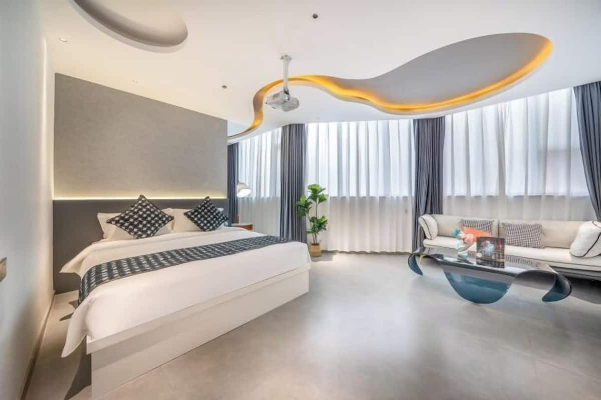 A modern bedroom with a bed, a sofa, and a glass coffee table.