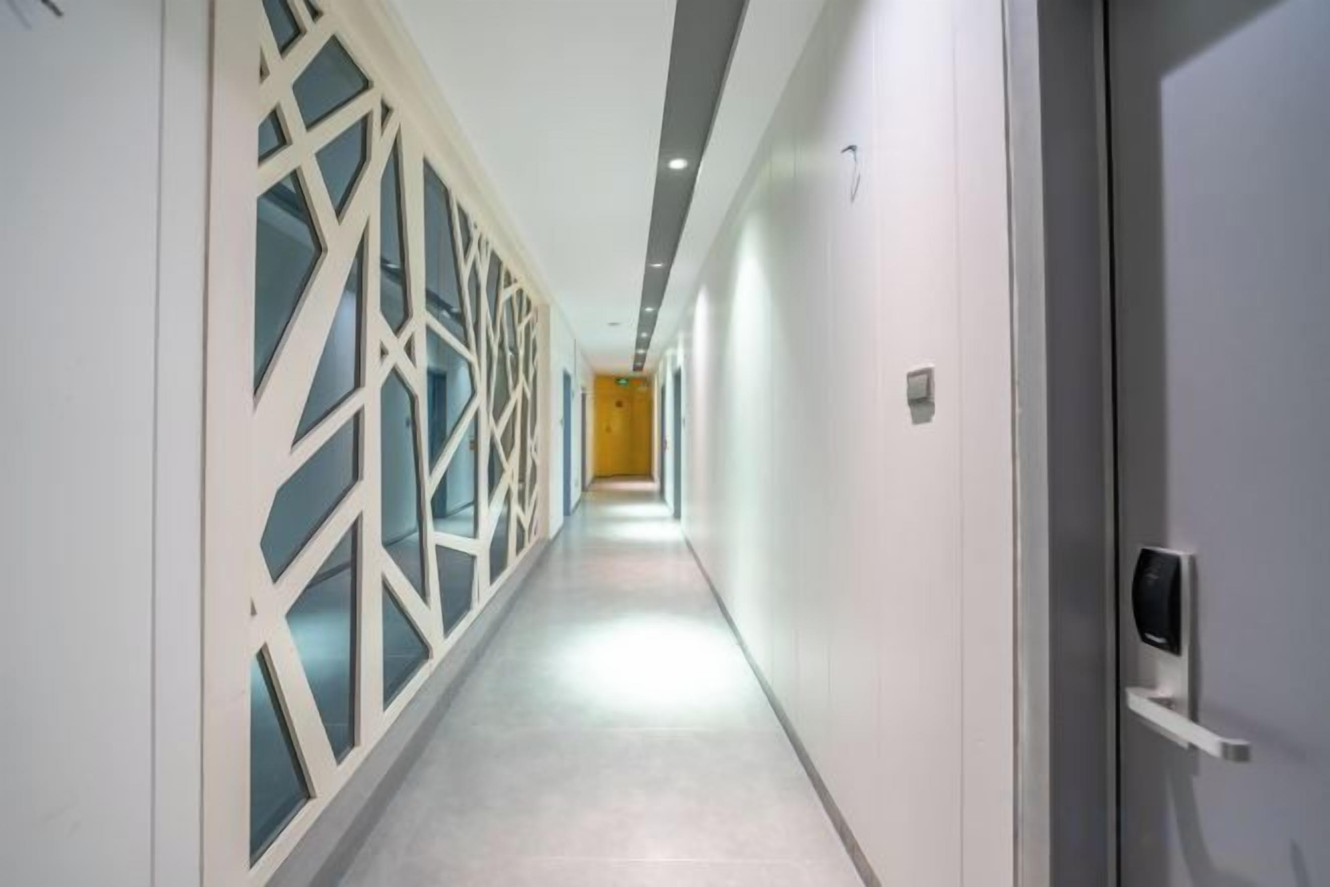 Un pasillo de diseño moderno, con una pared decorada con un patrón geométrico en un lado y una pared lisa en el otro.