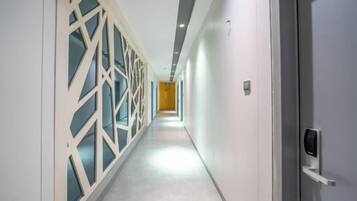 Un pasillo de diseño moderno, con una pared decorada con un patrón geométrico en un lado y una pared lisa en el otro.