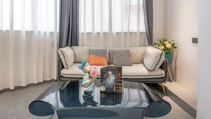 A modern living room with a sofa, a glass coffee table, and a vase with flowers. - Zhiling Homestay (Five Star Street City Center) (Liuzhou)