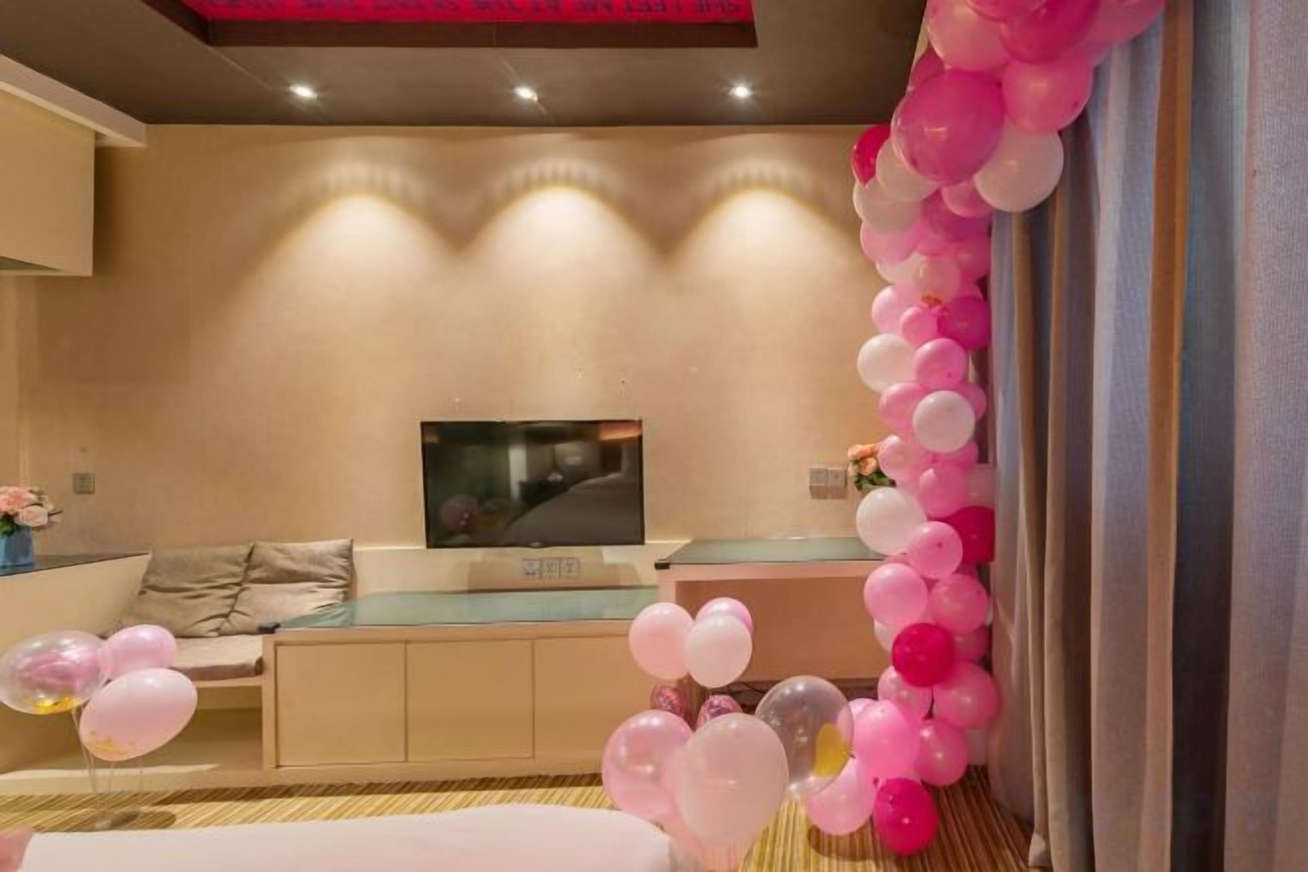 A living room with a flat-screen TV, a sofa, and a decorative balloon arch.