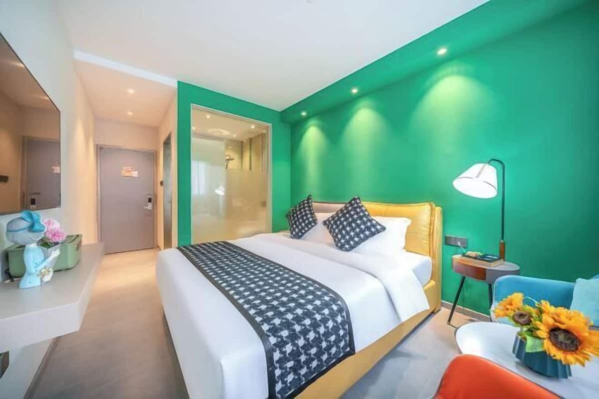 A modern hotel room with a bed, a nightstand, a lamp, and a chair.