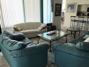 Relax in this stylish living room with a beige sofa, glass coffee table, and two armchairs.