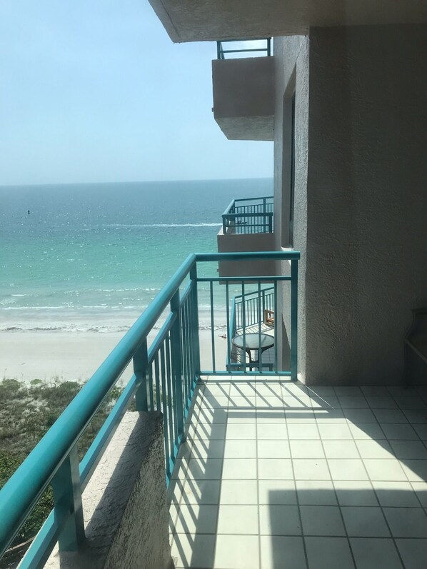 Enjoy the ocean view from this balcony with a table and chair.