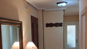 A hallway with a wooden floor, a marble counter with a lamp, a mirror, a radiator, and a door leading to another room. - Spacious and bright apartment near the beach..!! (Piedras Blancas)