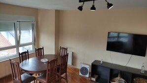 A dining area with a round table, chairs, a TV, and a radiator. - Spacious and bright apartment near the beach..!! (Piedras Blancas)