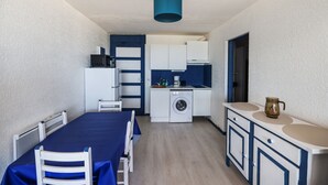 Una cocina compacta con lavadora, una mesa de comedor con sillas y una lámpara de techo azul.