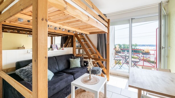 A cozy living room with a dark sofa, a white coffee table, and a wooden ceiling structure. - L'Effet Mer - Studio Apartment, Sleeps 4 (La Richardais)