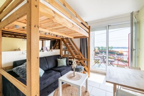 Een gezellige woonkamer met een donkere bank, een witte salontafel en een houten plafondconstructie.