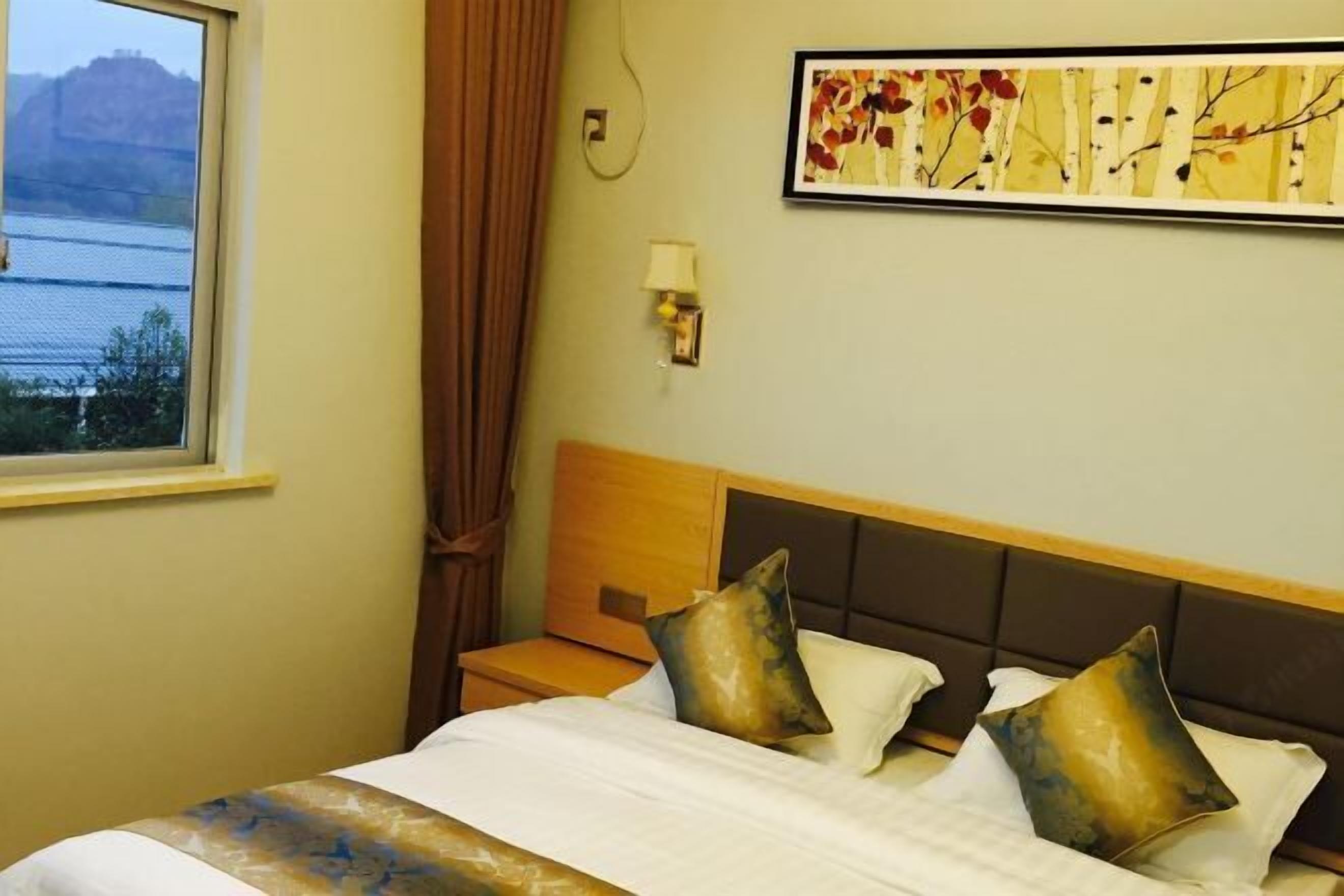 Une chambre d’hôtel avec un lit, une table de chevet, une lampe et un tableau au mur.