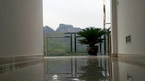 Ein Flur mit einer Glastür, die auf einen Balkon mit Bergblick führt.