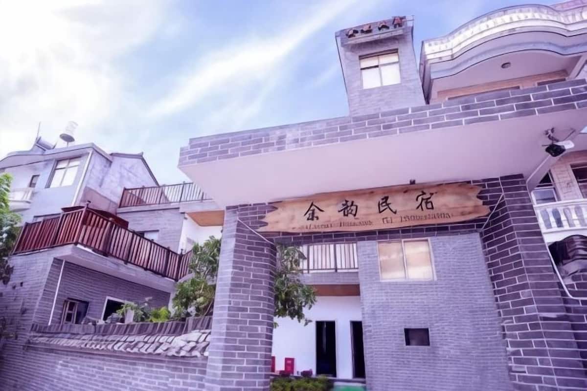 A building with a signboard, brickwork, and a balcony.