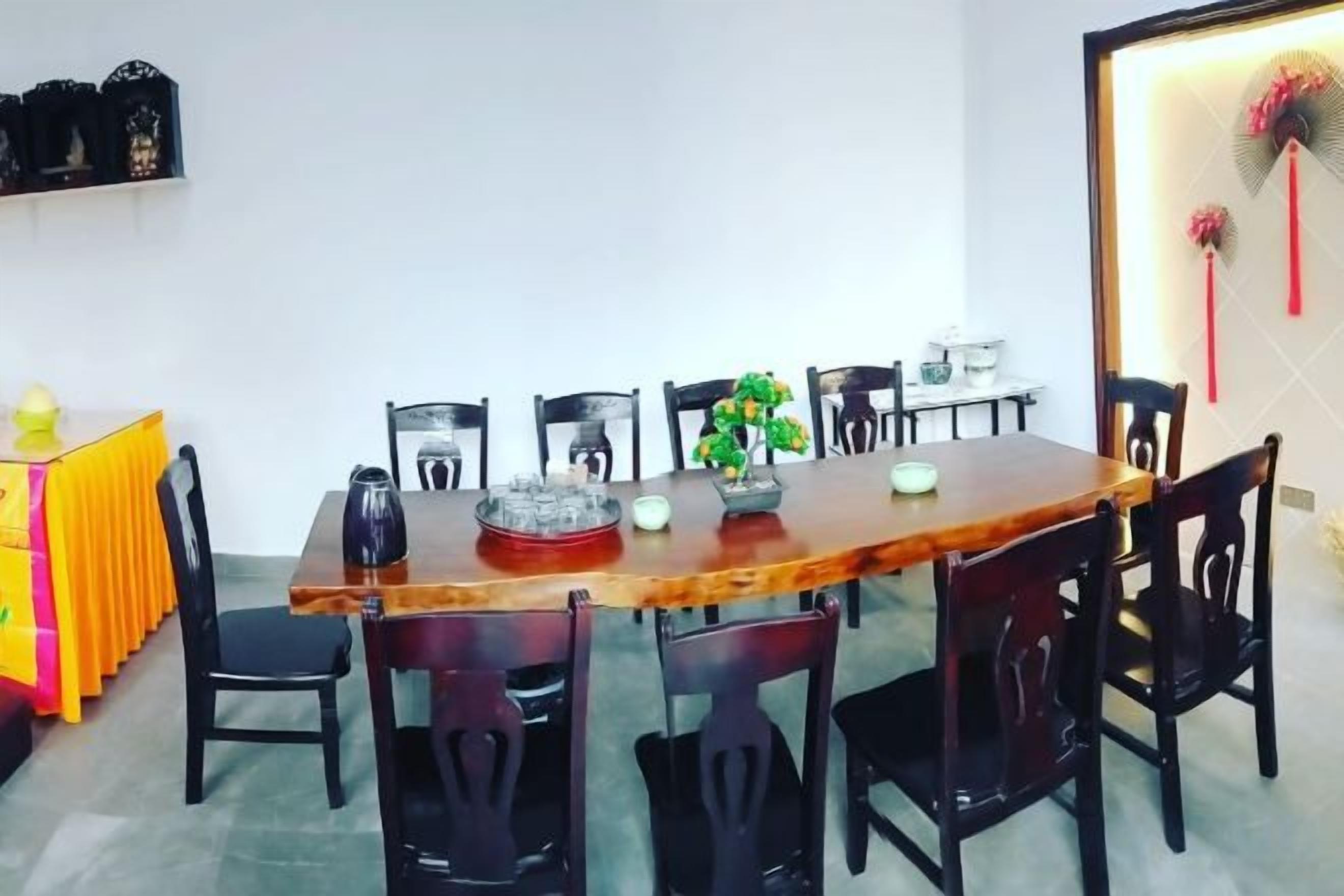 Zona pranzo con tavolo in legno, sedie nere e un vaso decorativo.