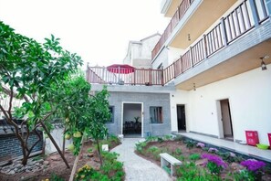 A residential building with a covered outdoor area, a pathway, and a small garden with plants and a bench. - Yuyun Hostel (Tiantai County)