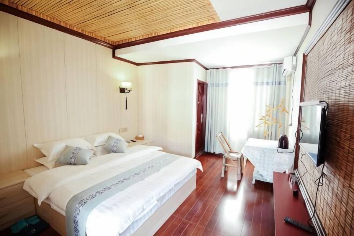 A hotel room with a bed, bedside table, chair, and a television.