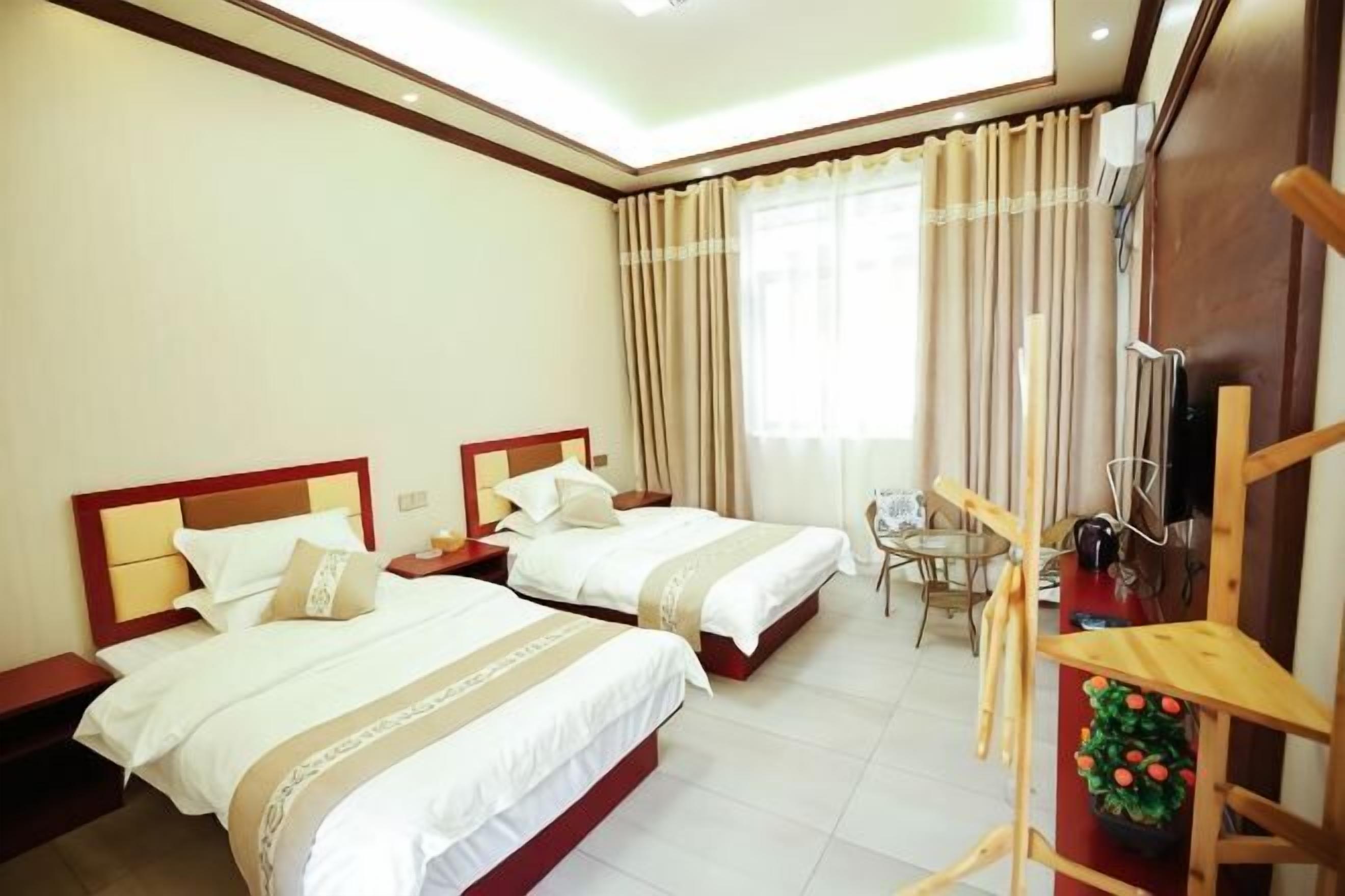 Una habitación de hotel con dos camas, una mesita pequeña y una silla.