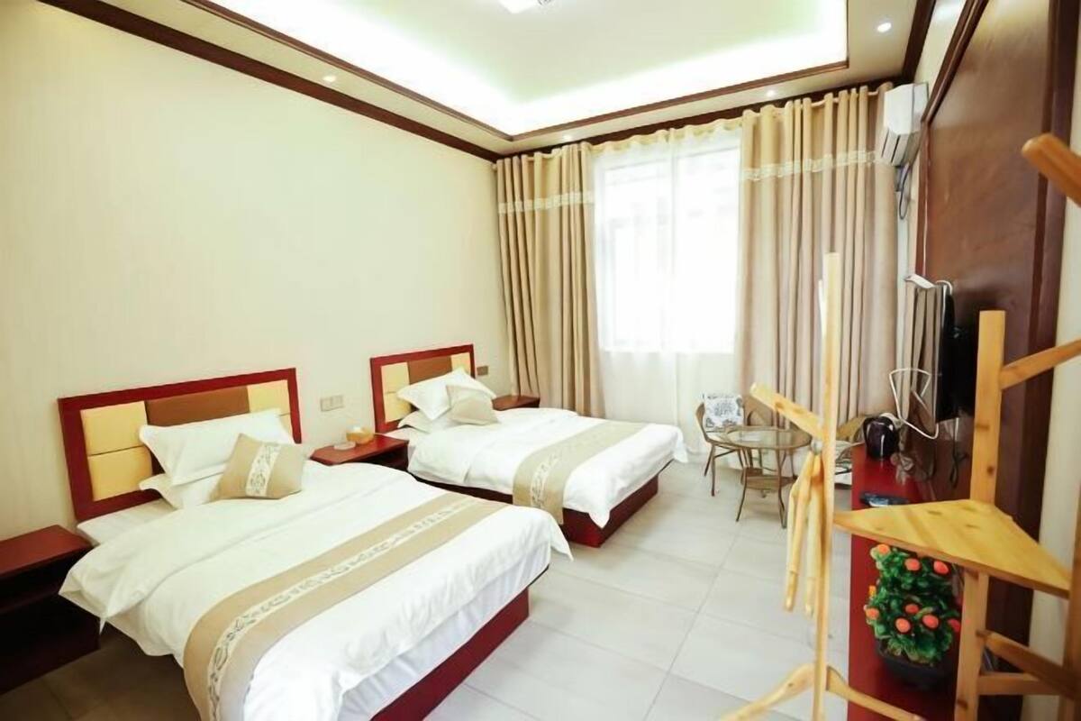 A hotel room with two beds, a small table, and a chair.