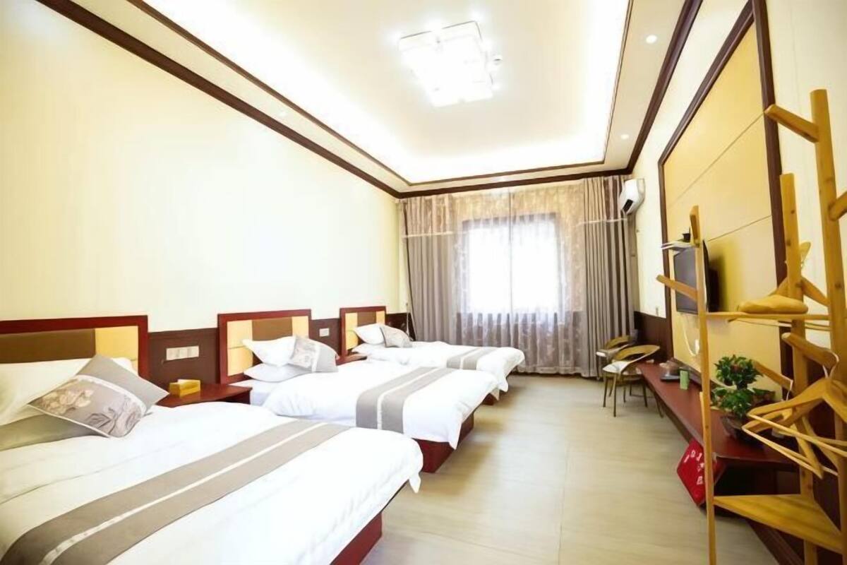 A hotel room with three beds, a desk, and a chair.