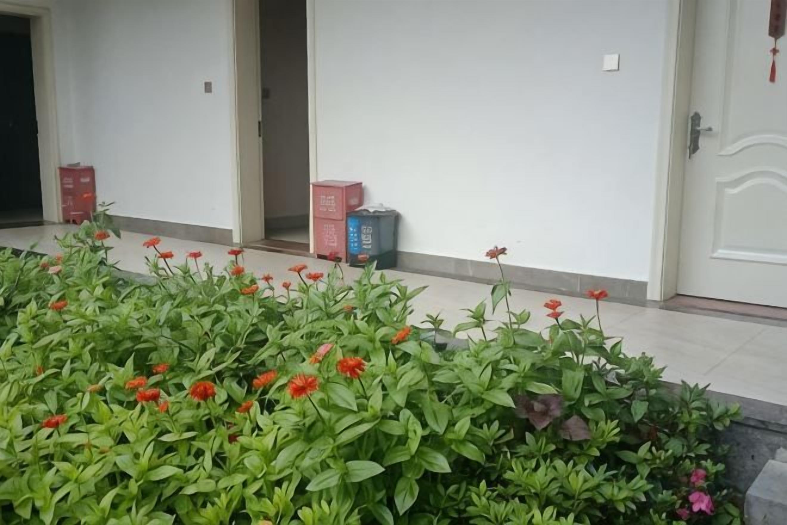 Entrada de un hotel con un cantero de flores al frente y una puerta a la derecha.