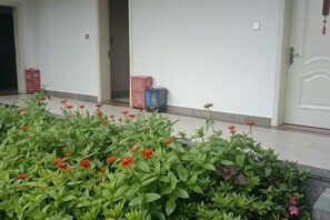 L’entrée d’un hôtel, avec un parterre de fleurs au premier plan et une porte sur la droite.