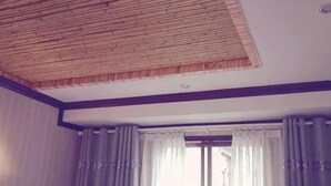 A room with a sloped ceiling, a large window with curtains, and a visible ceiling vent. - Yuyun Hostel (Tiantai County)