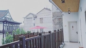 A balcony with a wooden railing, a red umbrella, and traditional architecture in the background. - Yuyun Hostel (Tiantai County)