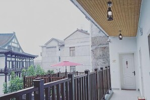 A balcony with a wooden railing, a red umbrella, and traditional architecture in the background. - Yuyun Hostel (Tiantai County)