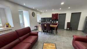 Un salon moderne avec un canapé en cuir rouge, une table basse en bois et un coin repas comprenant une table et des chaises en bois.