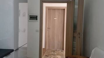A hallway with a wooden door, a bench, and a tiled floor.