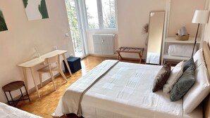 A bedroom with a bed, a desk, a chair, and a radiator.