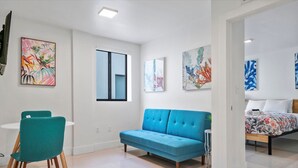 A modern living room with a blue sofa, teal chairs, and artwork on the walls. - Miami Suite 303 (Miami)