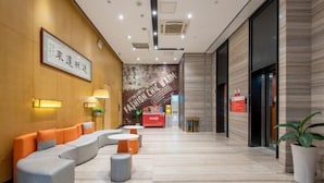 A modern lobby with a curved seating area, a reception desk, and a large poster on the wall. - IU Hotel (Zhongshan Xiaolan Parkway Plaza) (Zhongshan)