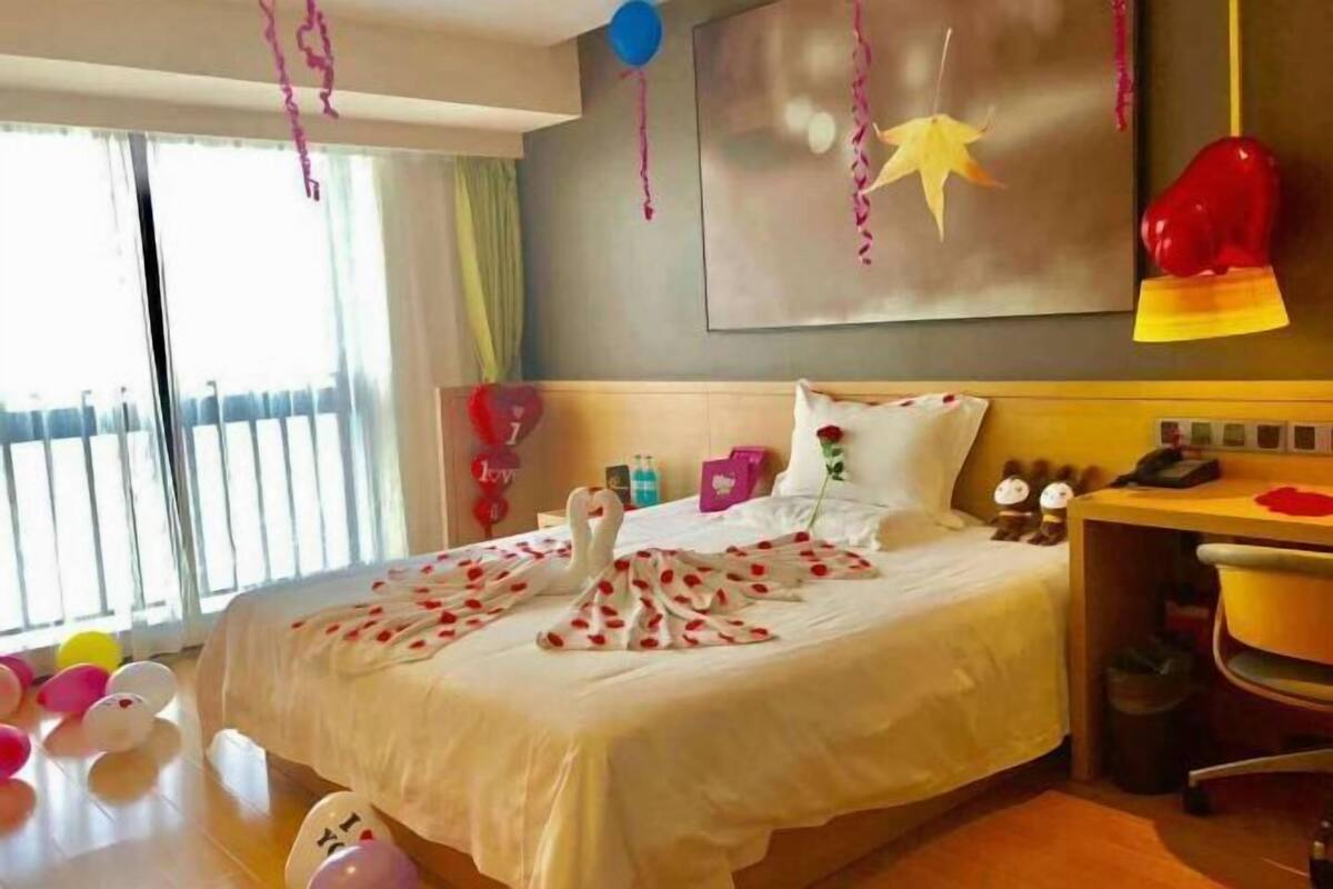 A hotel room with a bed, a desk, and a chair. There are balloons on the floor and a star decoration on the wall.