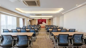 A conference room with rows of tables and chairs, air conditioning vents, and a carpeted floor. - IU Hotel (Zhongshan Xiaolan Parkway Plaza) (Zhongshan)