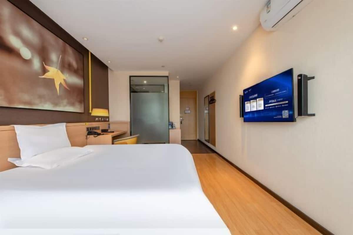 A hotel room with a bed, a TV mounted on the wall, and a door leading to the bathroom.