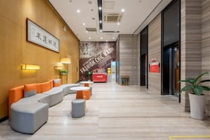 A hotel lobby with a reception desk, seating area, and a wall with a fashion-themed mural. - IU Hotel (Zhongshan Xiaolan Parkway Plaza) (Zhongshan)