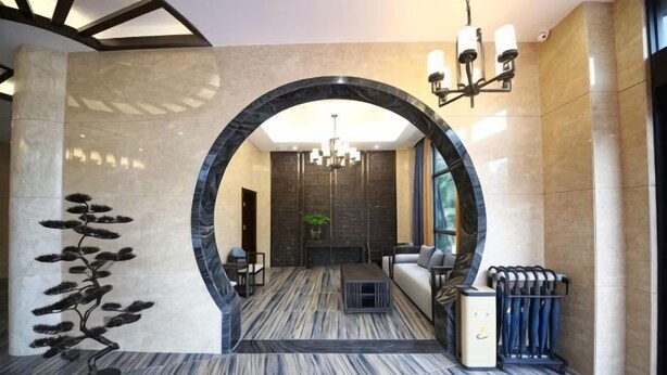 A lobby with a marble floor, a large archway, a chandelier, and a seating area with a fireplace. - Mingdelou Hotel (Yichang)