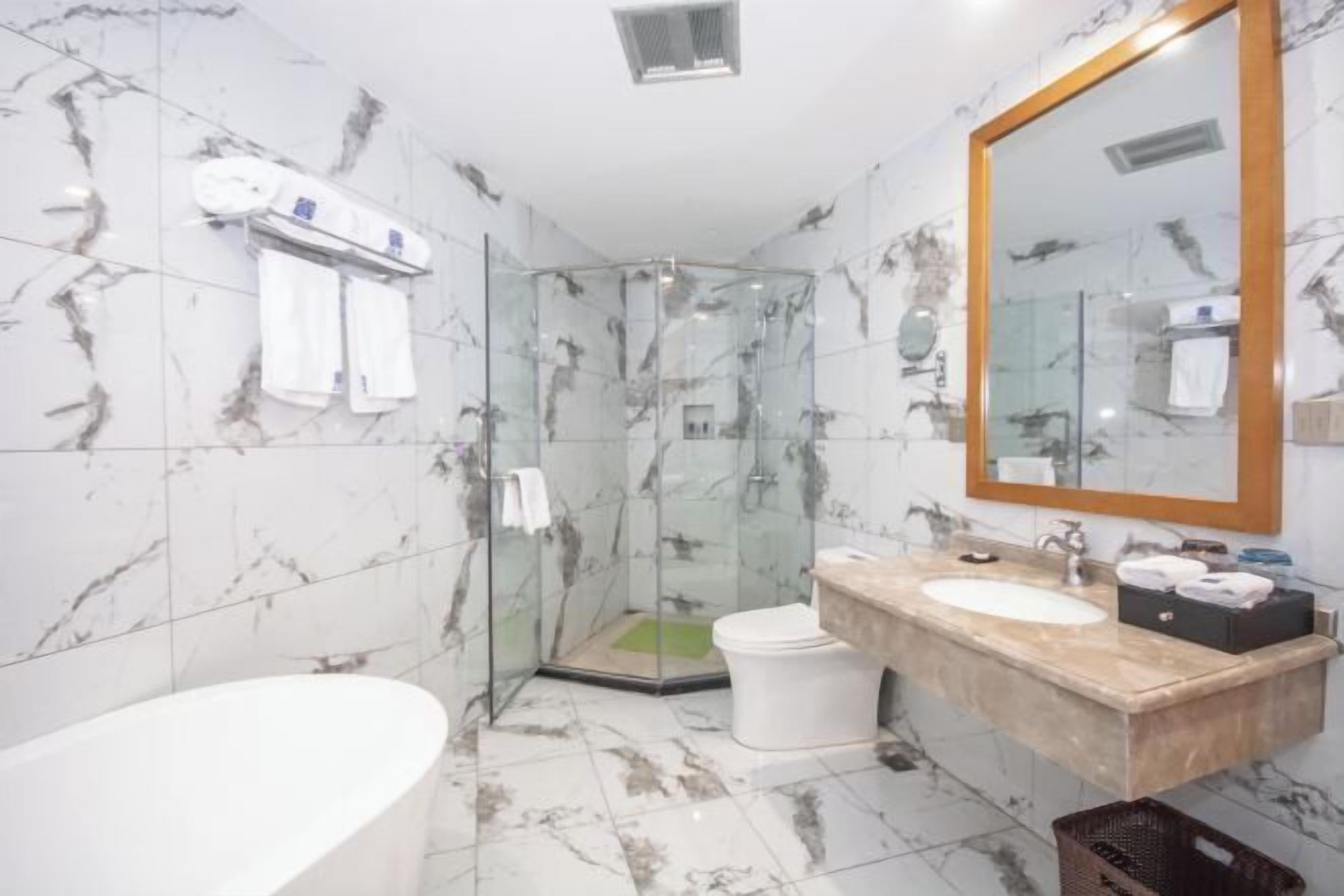 A bathroom with a glass-enclosed shower, a white bathtub, and a marble-tiled floor.