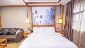 A hotel room with a bed, a sofa, and a wall-mounted artwork. - Mingdelou Hotel (Yichang)