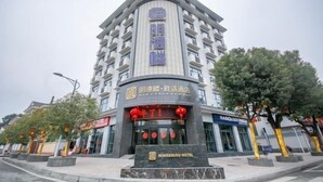 A hotel with a modern design, featuring a prominent entrance with a signboard and red lanterns. - Mingdelou Hotel (Yichang)