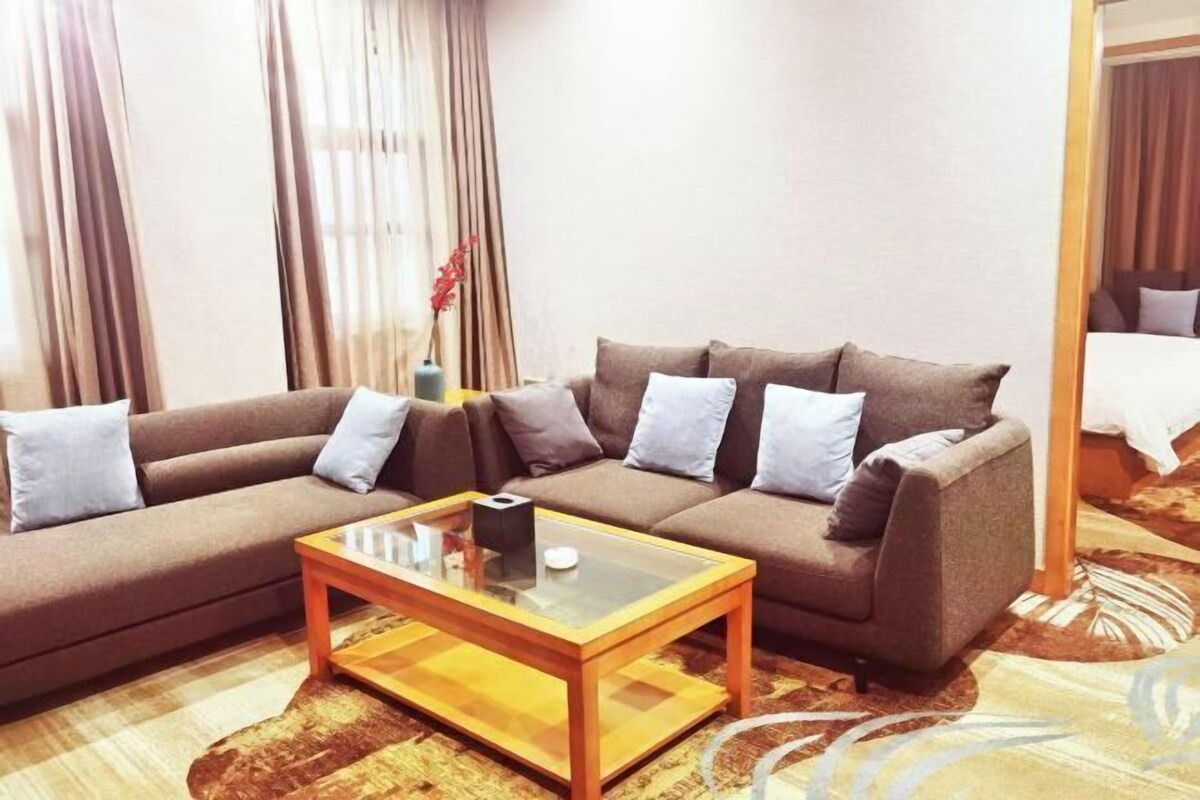 A living room with a sofa, a glass coffee table, and a vase with flowers.