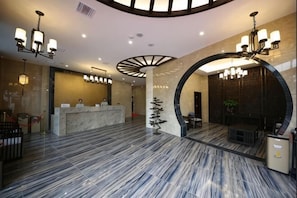 Vestíbulo de hotel con mostrador de recepción, zona de estar y un gran elemento decorativo circular en la pared.