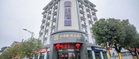 A multi-story hotel with a prominent entrance, signage, and a landscaped area with trees.